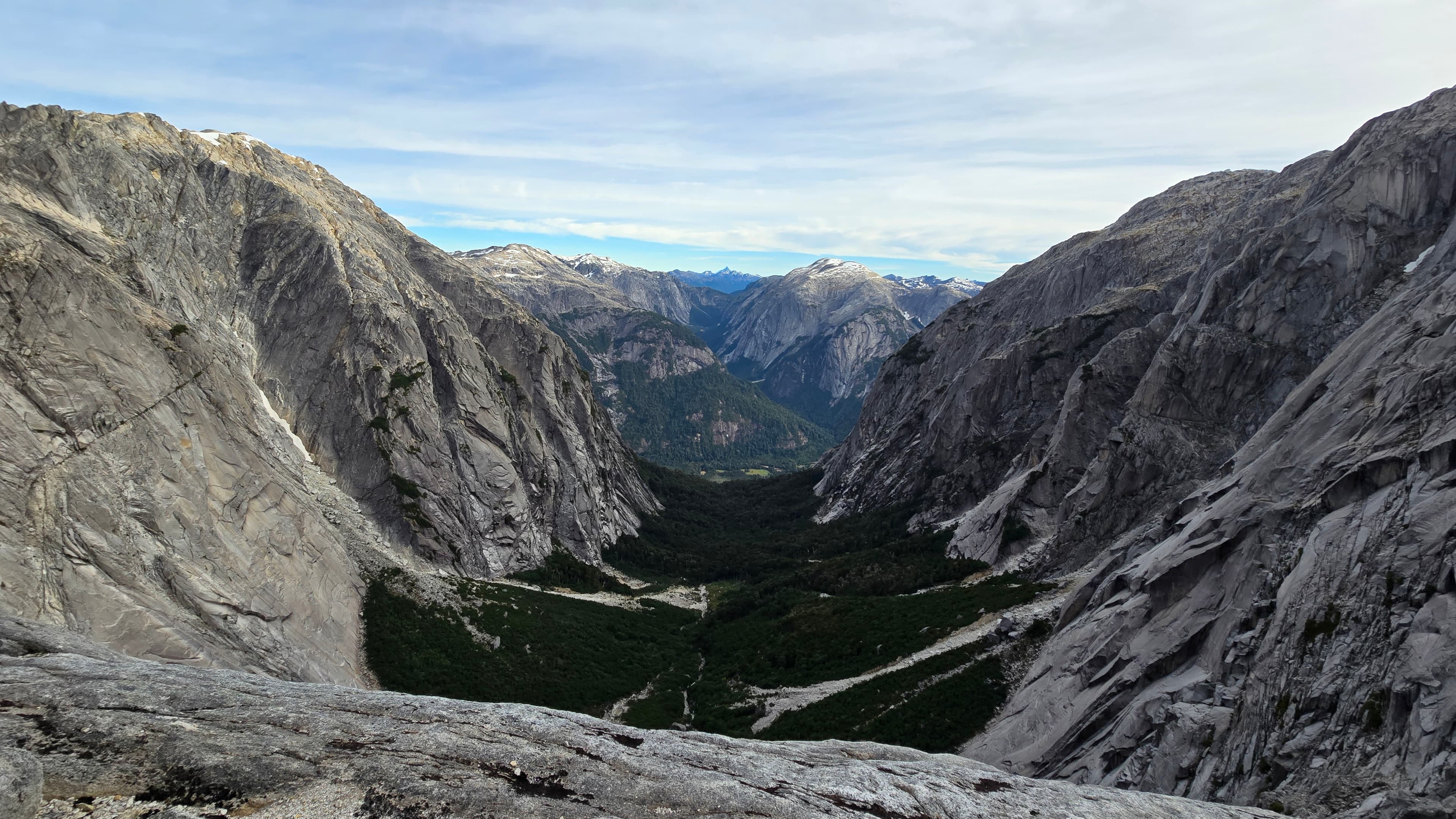 Granite mountain walls rising above a forested valley in Chile.